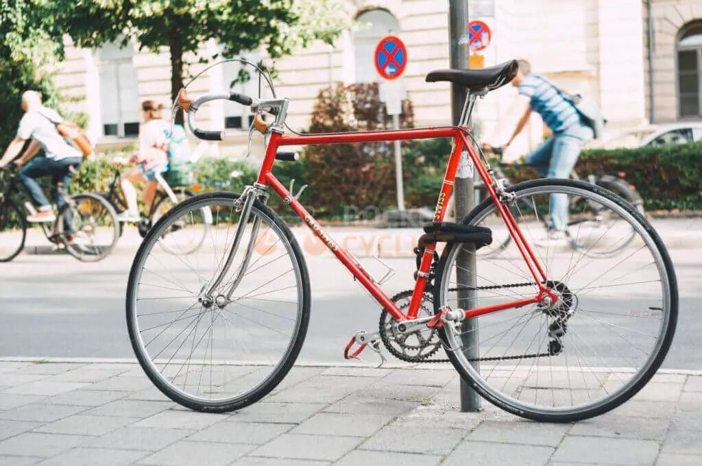 A red bicycle leaning against a pole.