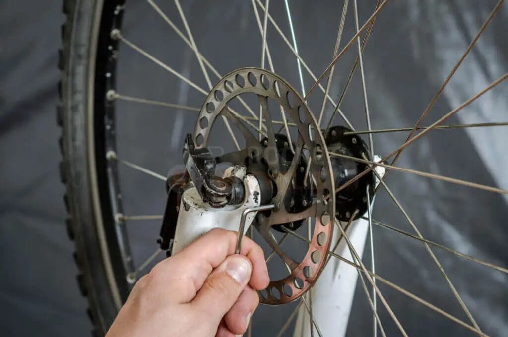 A person fixing a bicycle wheel on a black background.