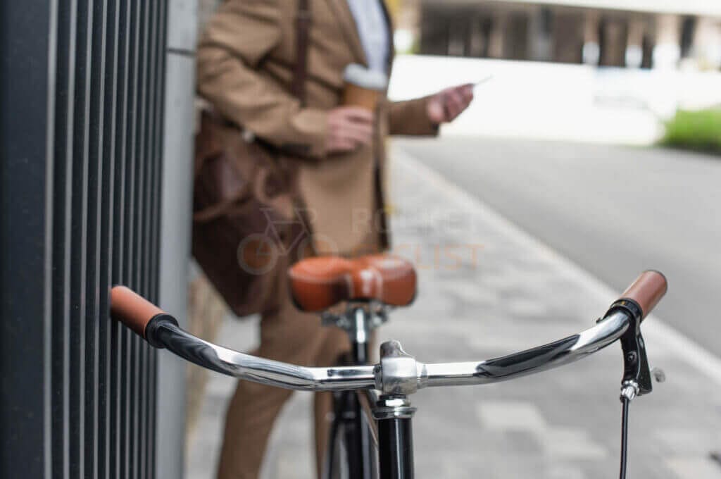 A businessman standing next to a bicycle with a cell phone.