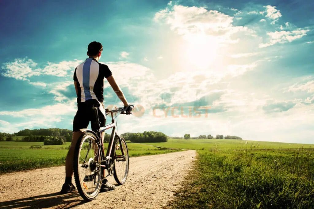 A man riding a bicycle on a dirt road.