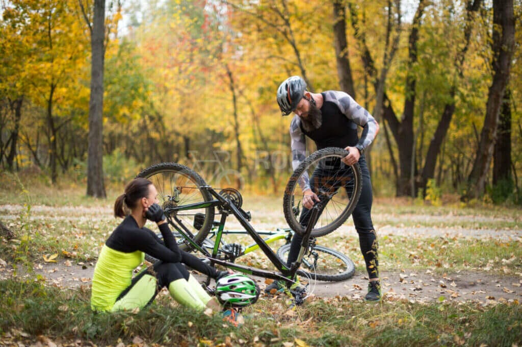 Two people fixing a bicycle in a park.