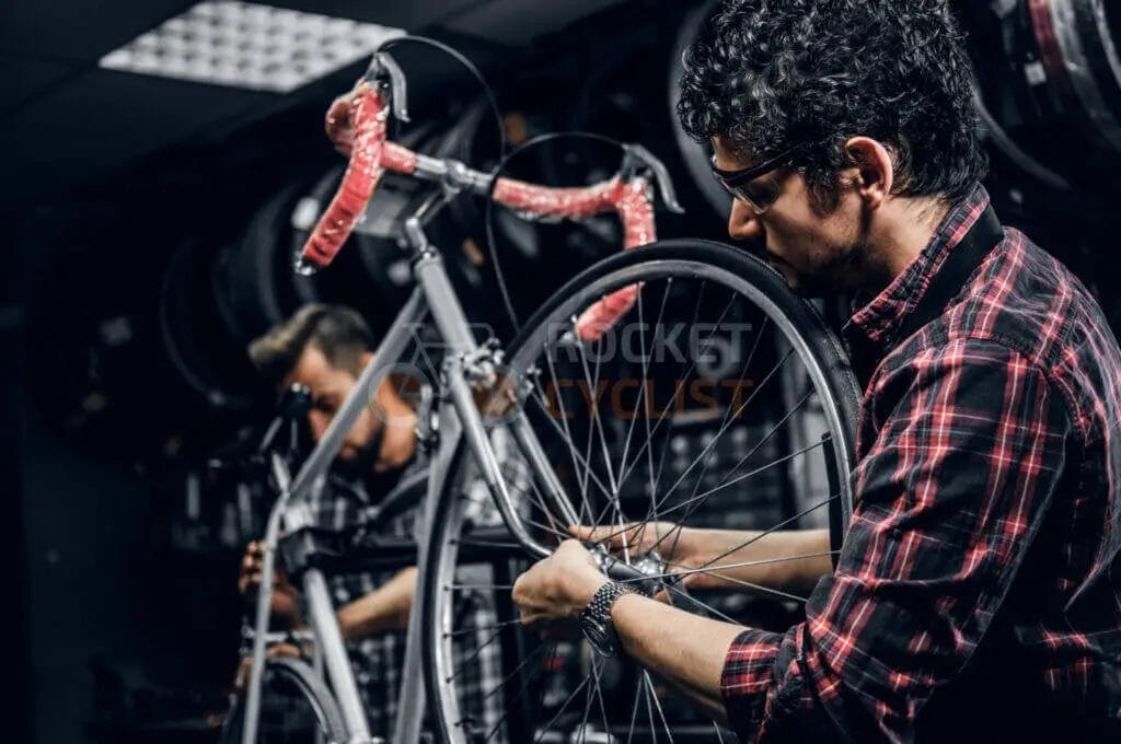 Two men working on a bicycle in a shop.