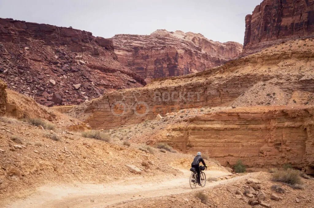 A man riding a bike on a dirt trail in the desert.