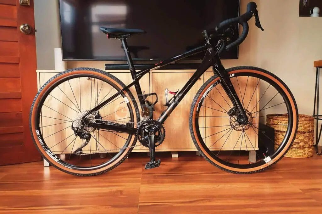 A black cyclocross bike parked in front of a television.