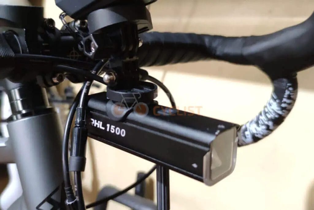 The handlebar of a bicycle with a light attached to it.