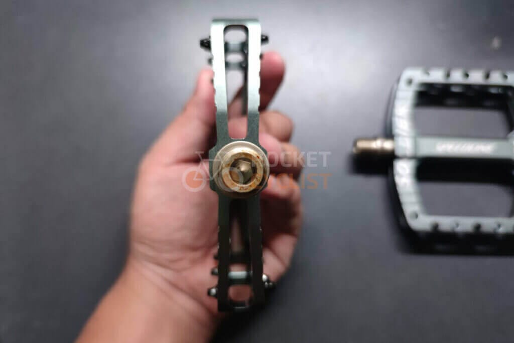 A person holding a bike pedal with a green handle.