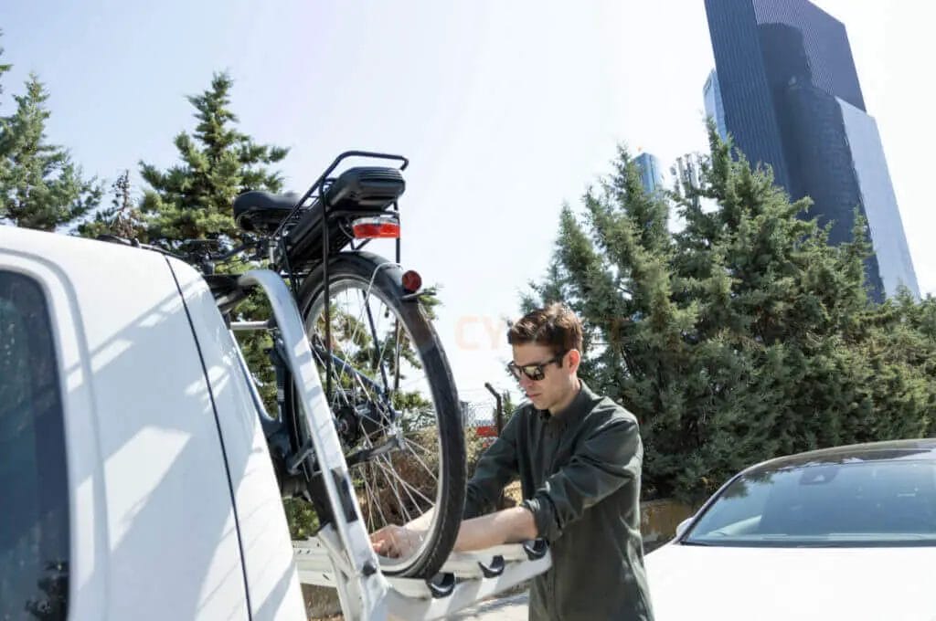 A man putting a bike on the back of a car.