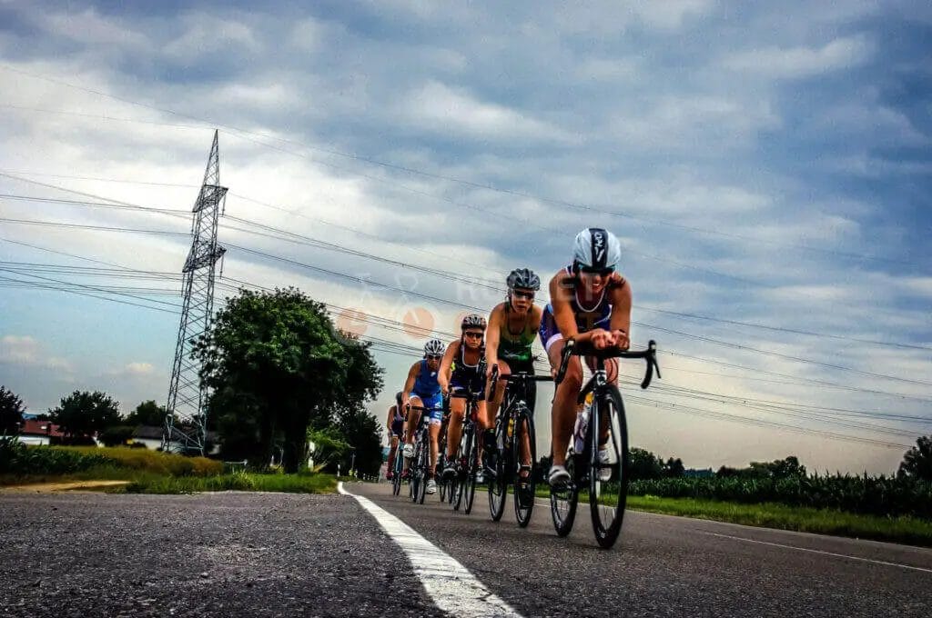 A group of cyclists riding down a road under a cloudy sky.