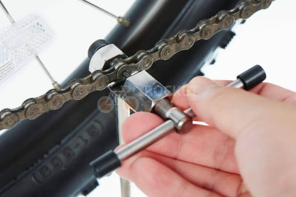 Person using a chain tool to repair a bicycle chain.