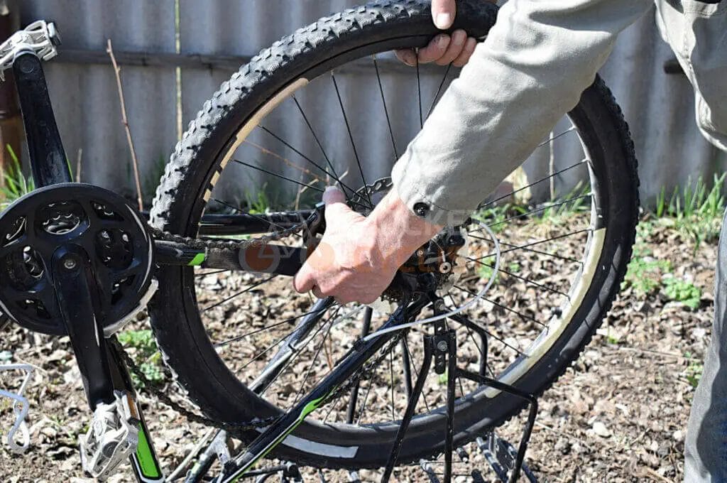 Person repairing a bicycle wheel outdoors.