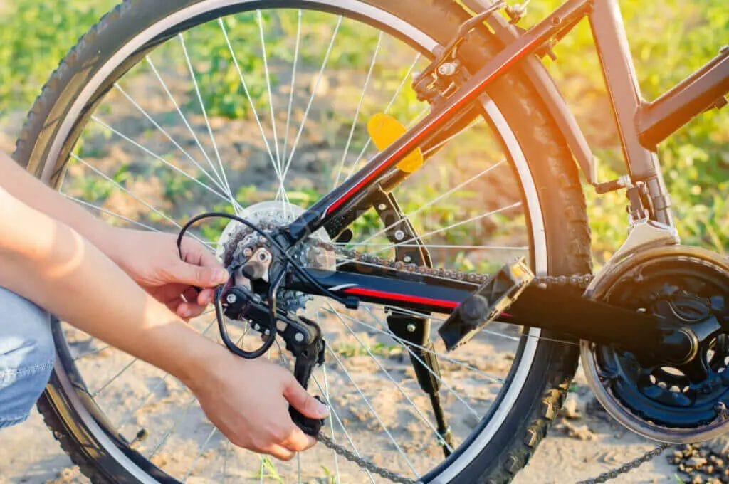 Person adjusting the rear derailleur of a bicycle.