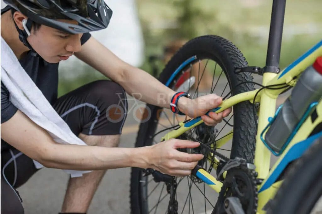 Cyclist wearing a helmet adjusts the brakes on a bicycle.