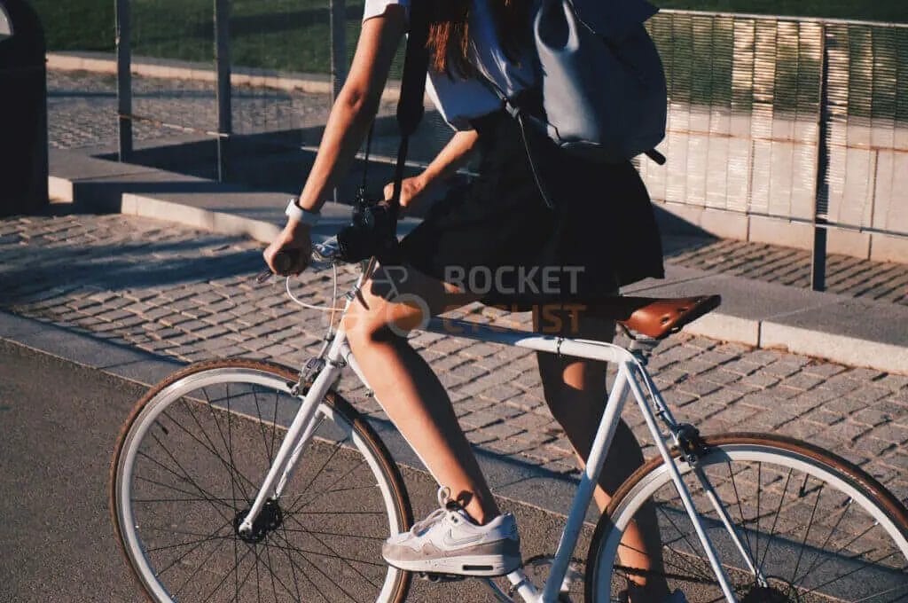 A young woman riding a bicycle with a backpack.