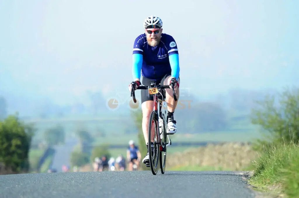 A man riding a bicycle down a country road.