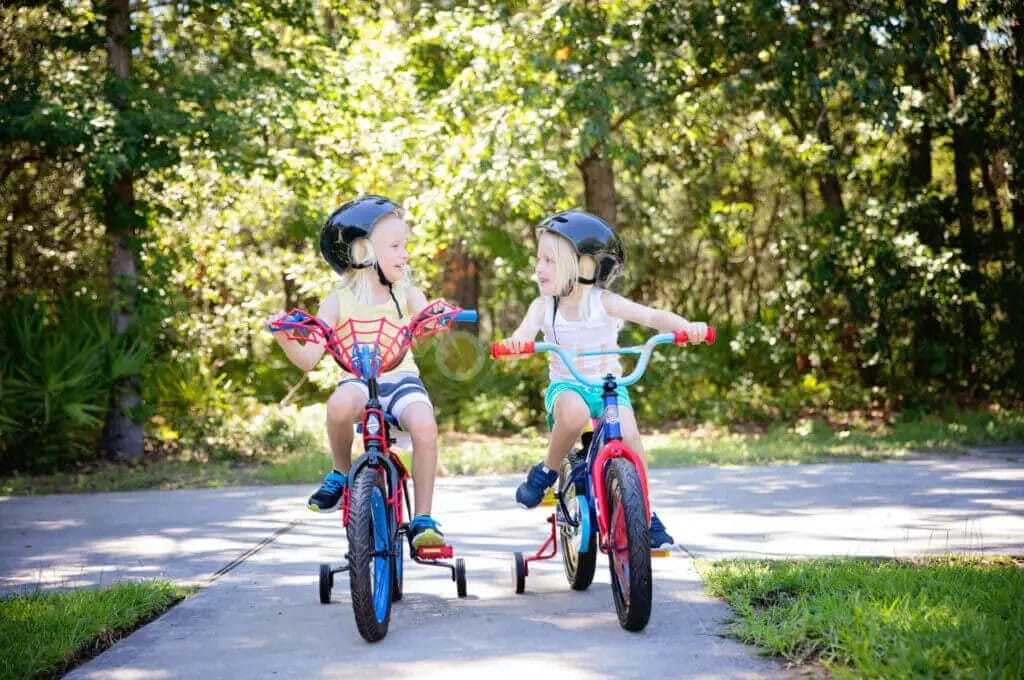 Two children riding bikes on a sidewalk.