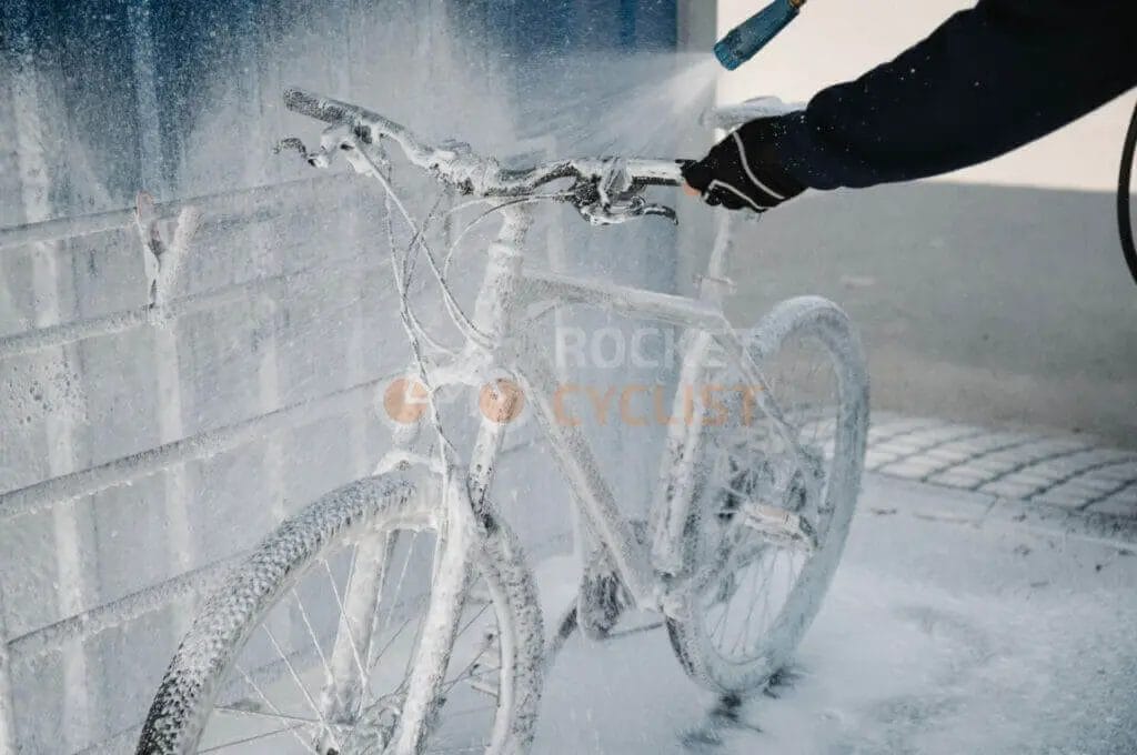 A person is spraying a bicycle with a hose.