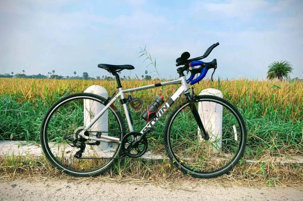 A bicycle leaning against a fence in a field.