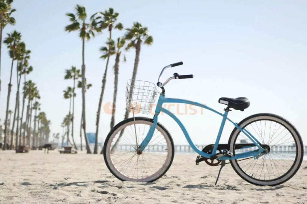 A blue bicycle is parked on the beach in front of palm trees.