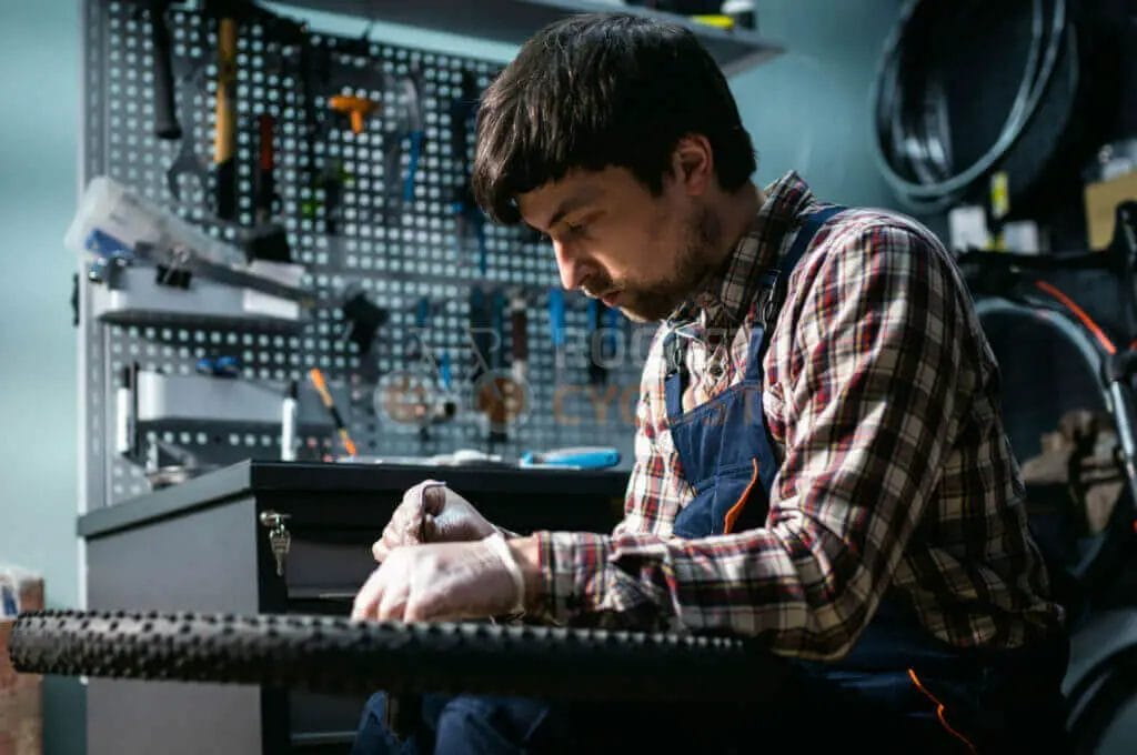 A man is working on a bicycle tire in a workshop.