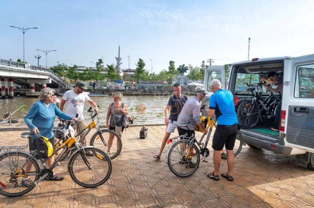 A group of people standing next to a van with bicycles.