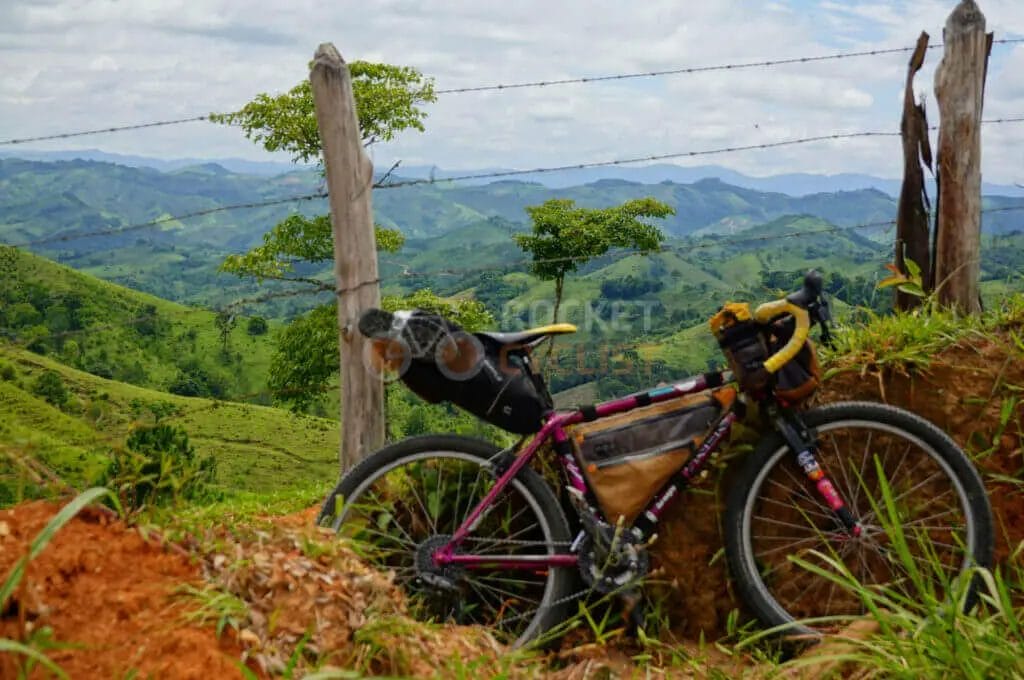 A bicycle is parked on a hillside with mountains in the background.