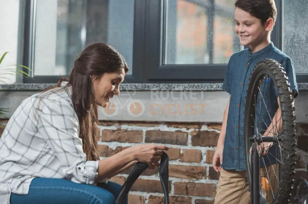 A woman and a boy fixing a bicycle tire.