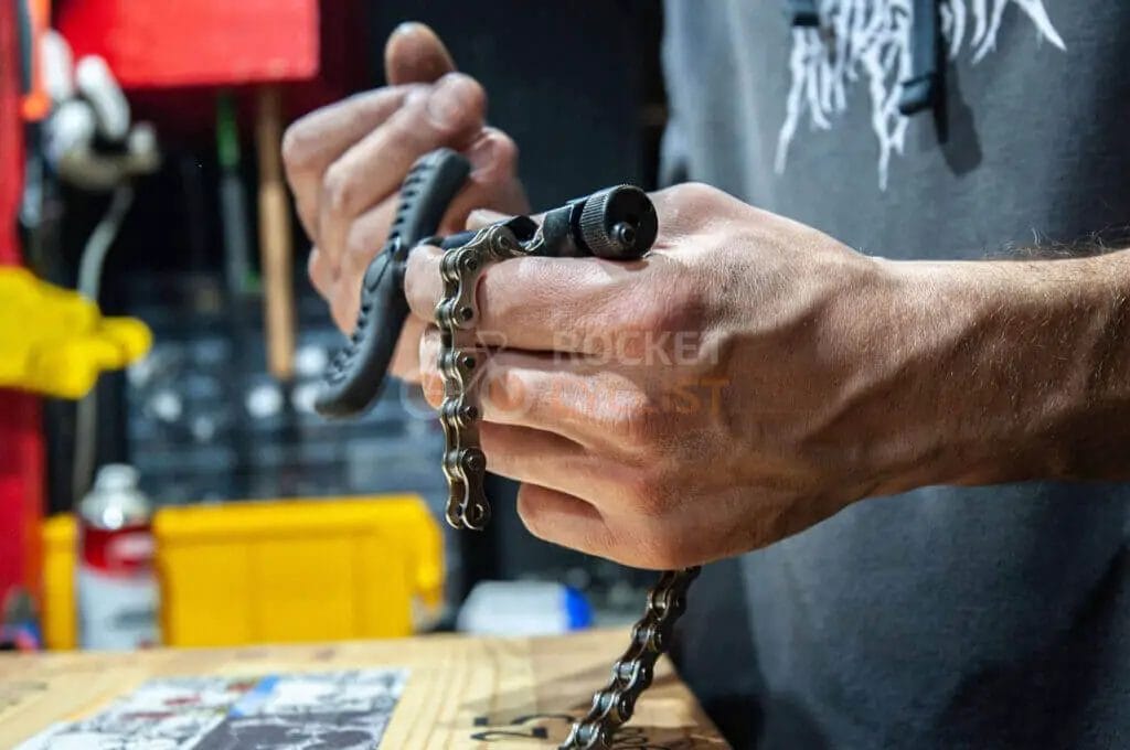 A man is working on a chain on a table.