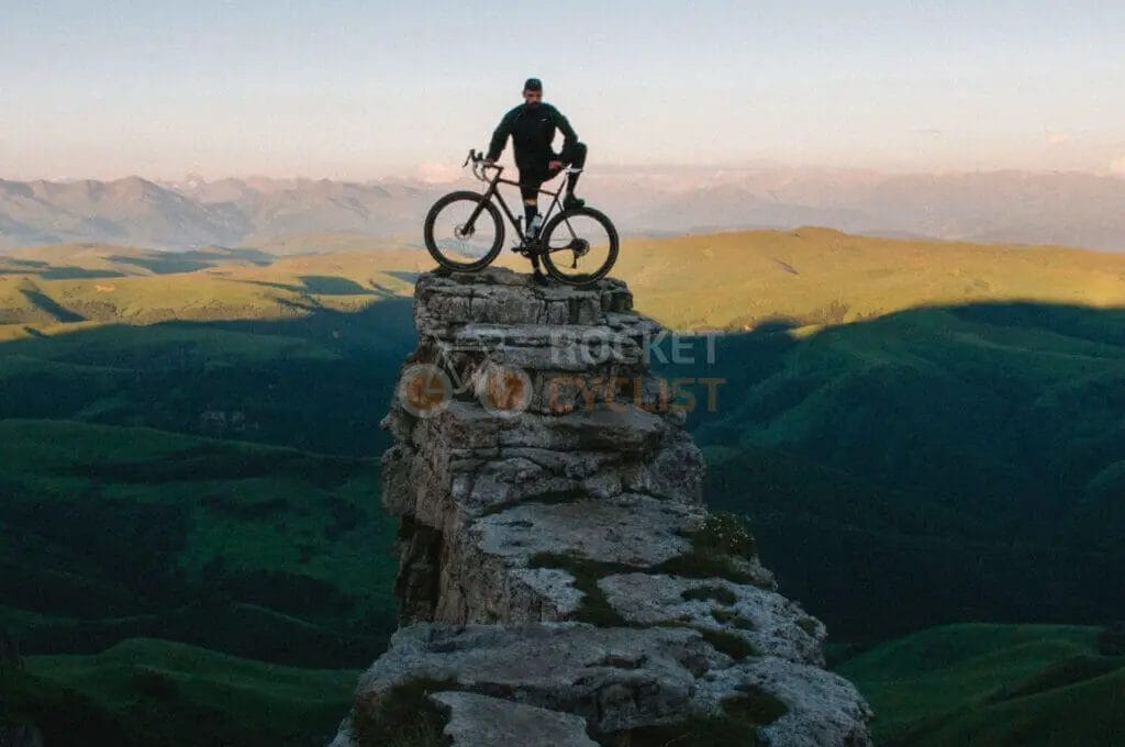A man standing on top of a mountain with his bike.