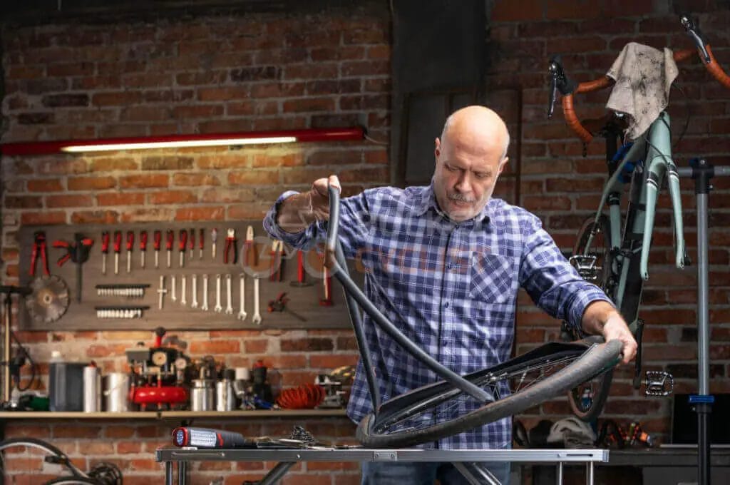 A man is working on a bicycle tire in a workshop.
