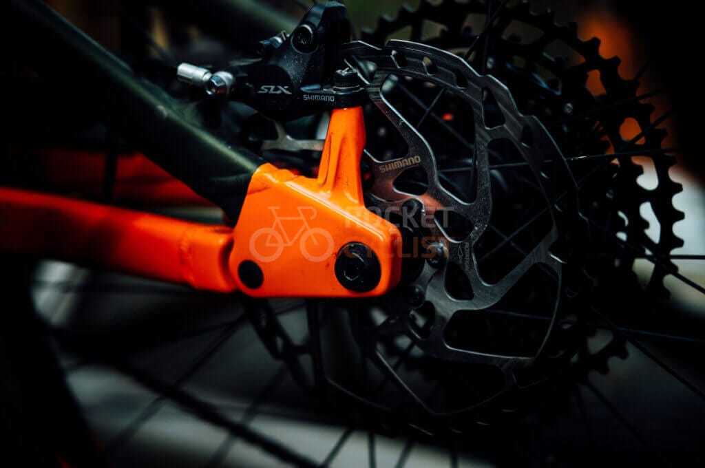 A close up of an orange bicycle chain and gears.