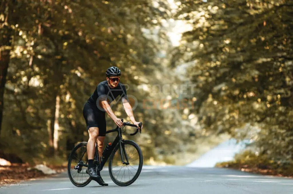 A man riding a bike on a road in the woods.