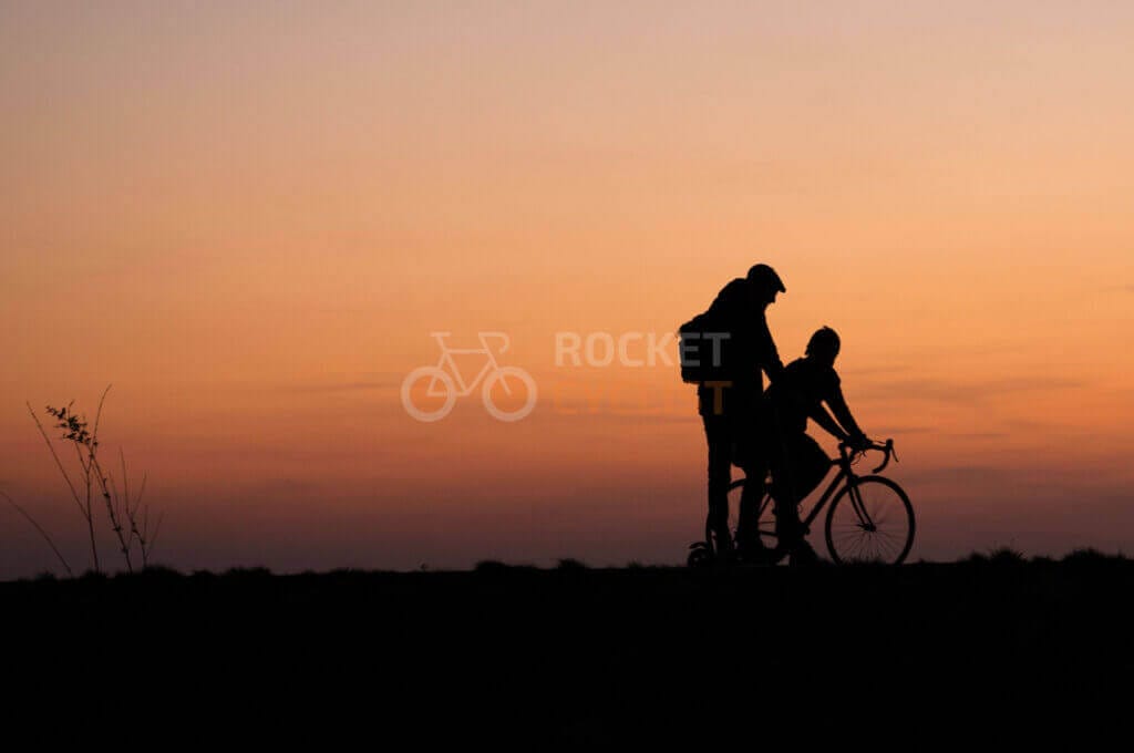 Silhouette of a couple riding bicycles at sunset.