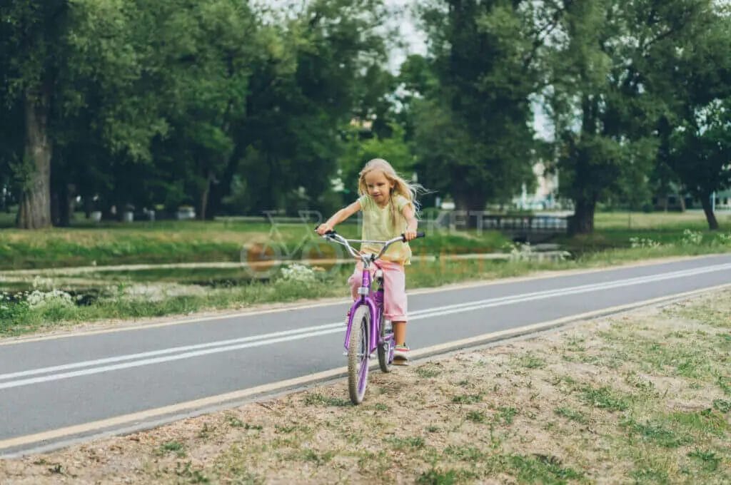 A little girl riding a bicycle in a park.