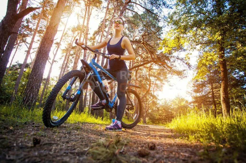 A woman is riding a mountain bike in the woods.