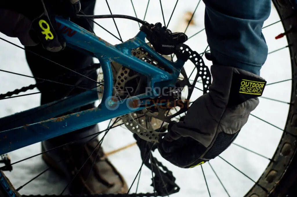 A person is working on a mountain bike in the snow.