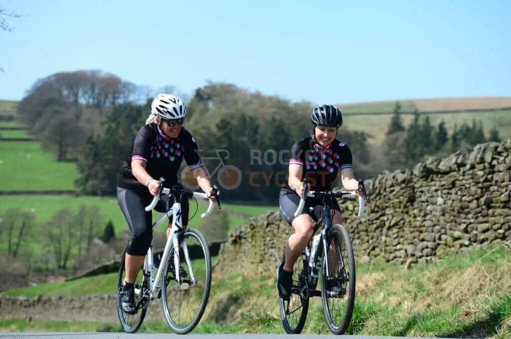 Two women riding bikes down a country road.