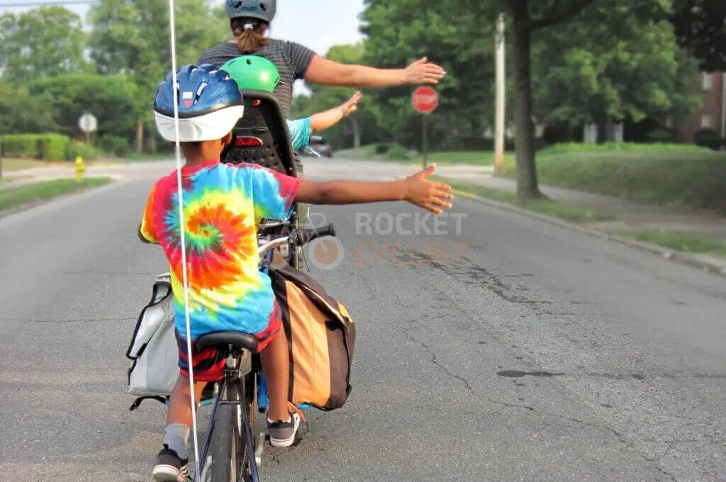 A man riding a bike with a child on his back.