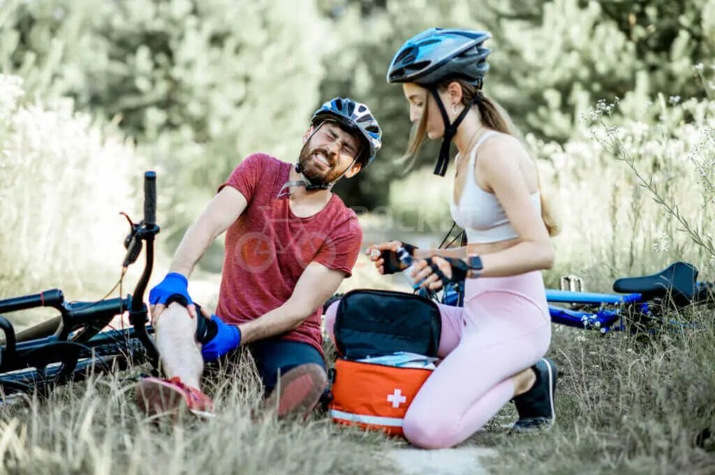 A man and woman are sitting on the ground next to a bicycle.