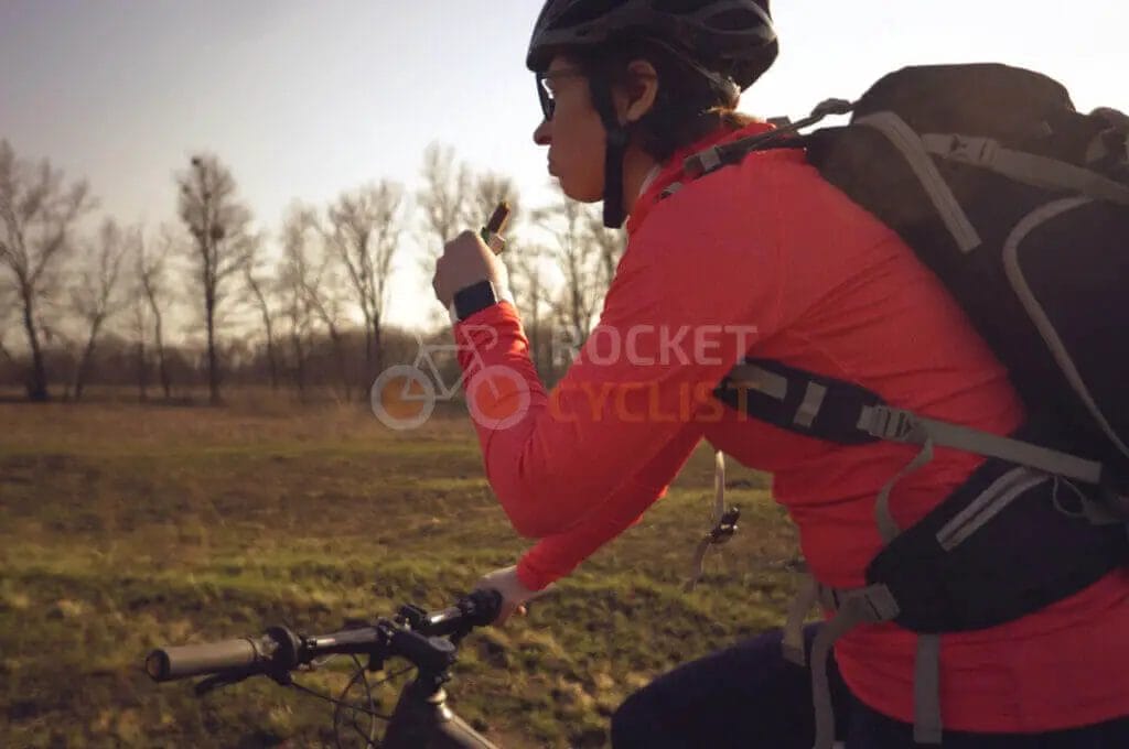 A woman riding a bike in a field with a backpack.