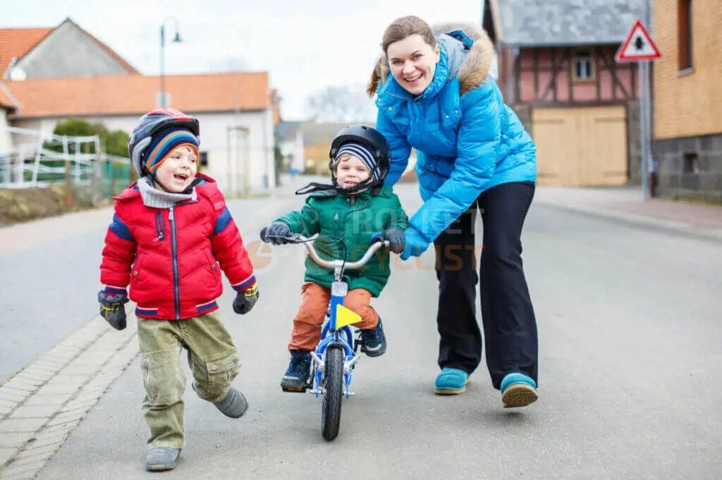 A woman with two children riding a bicycle on a street.