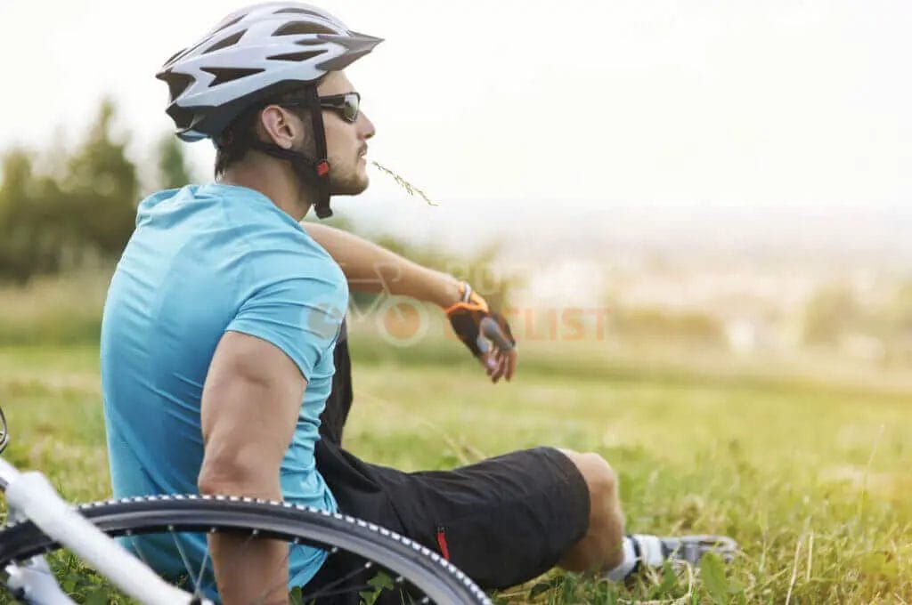 A man sitting on the grass with his bike.