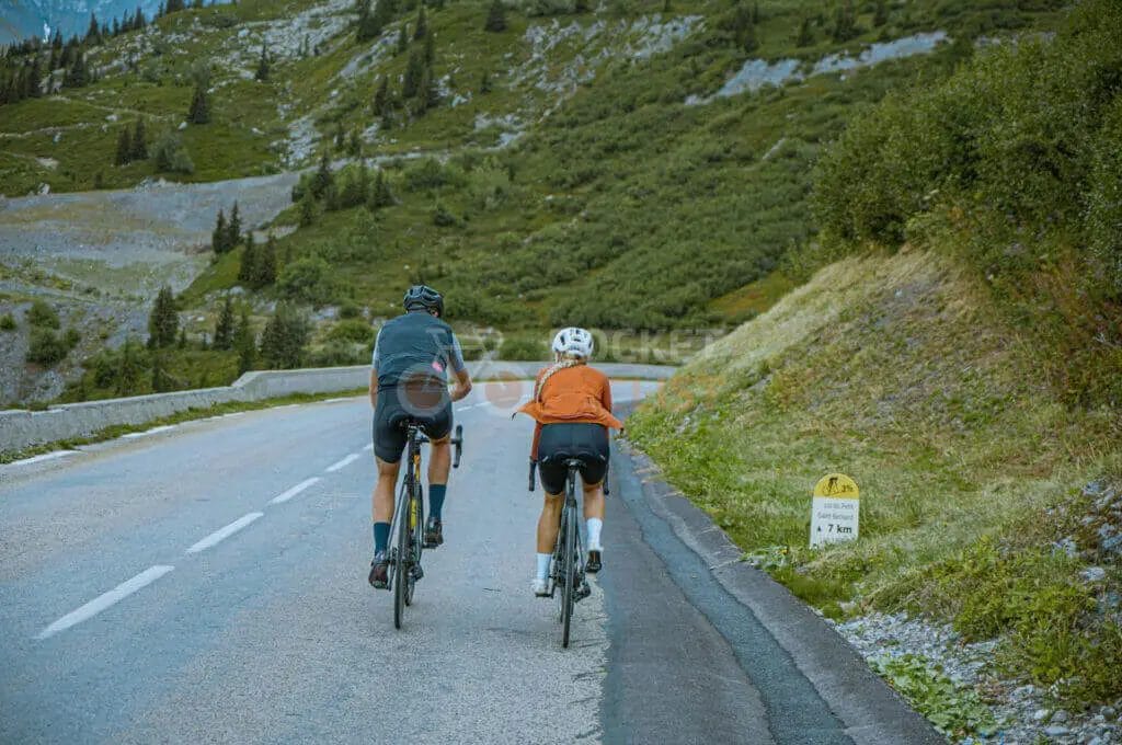 Two people riding bicycles down a mountain road.