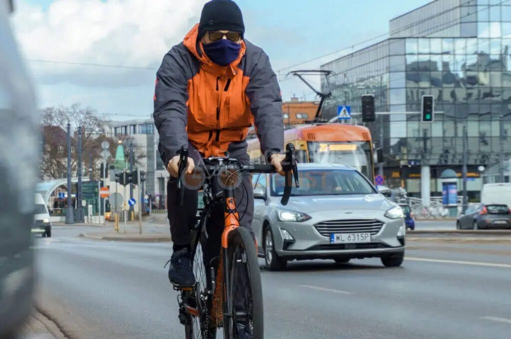 A cyclist wearing a face mask on a city street.