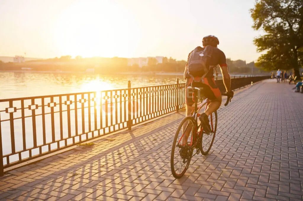 A man riding a bicycle along a path near a lake.