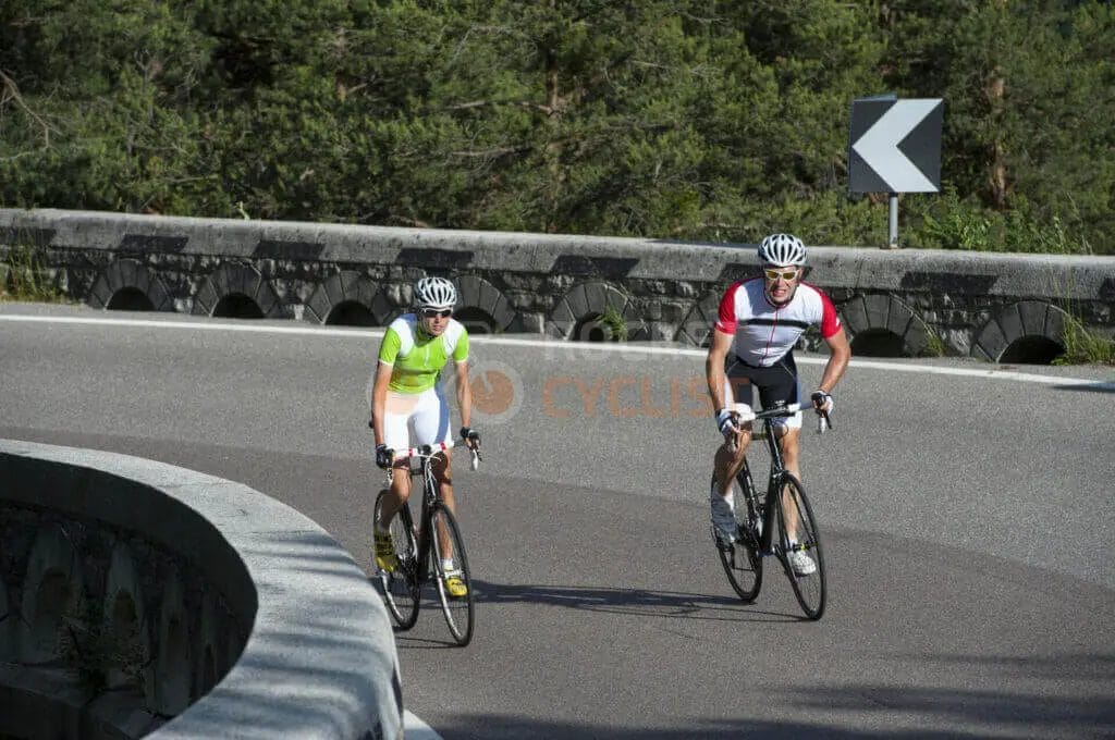 Two people riding bicycles down a road.