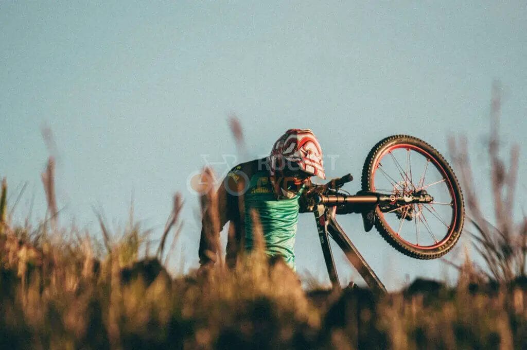A man fixing his mountain bike on the side of a hill.