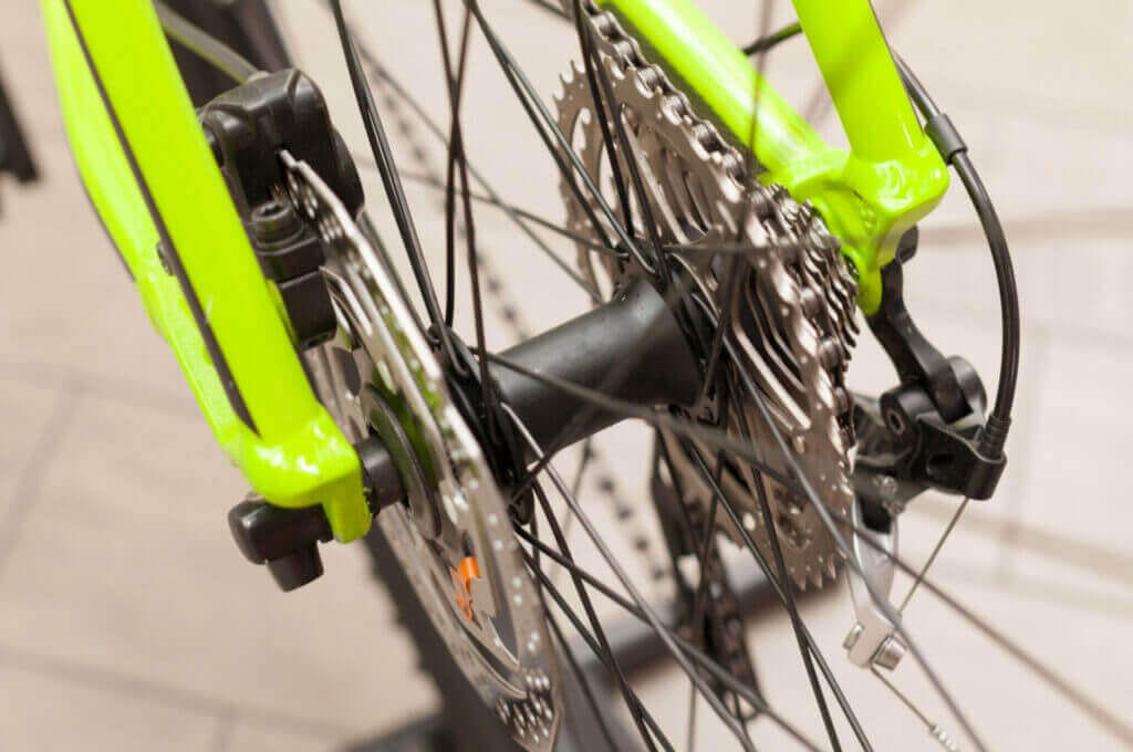 A close up of a green bicycle with a chain and gears.