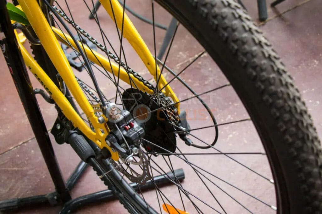 A yellow bicycle with a chain on a stand.