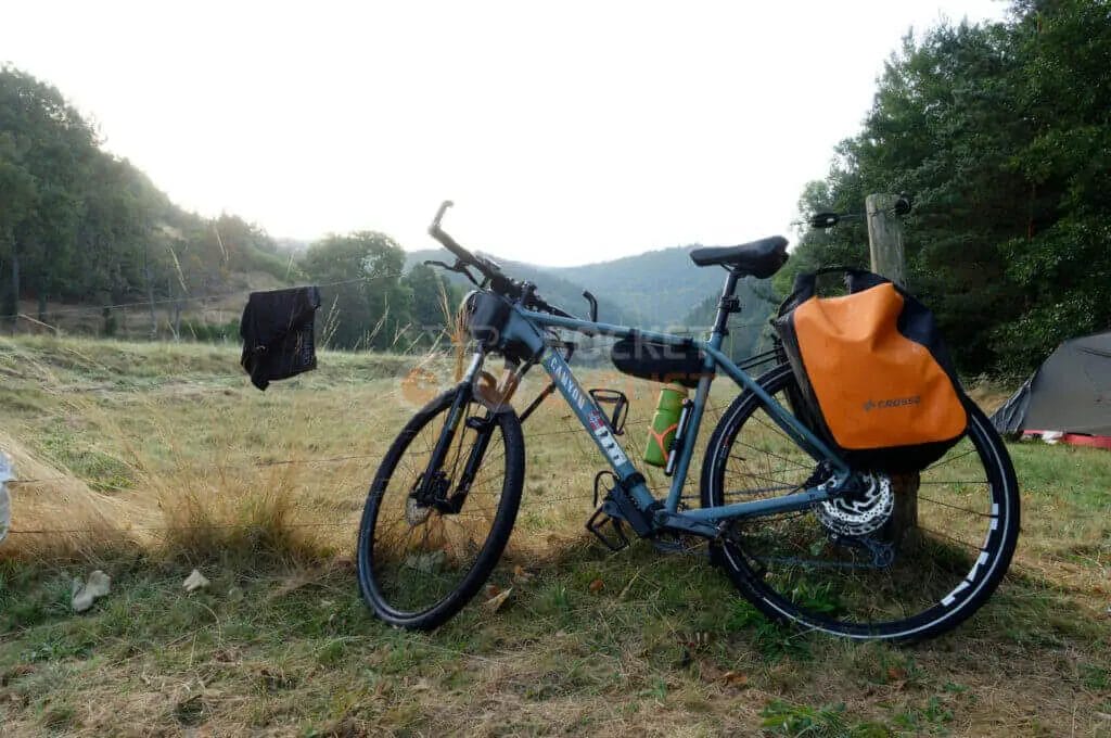 A bicycle is leaning against a tent in a field.