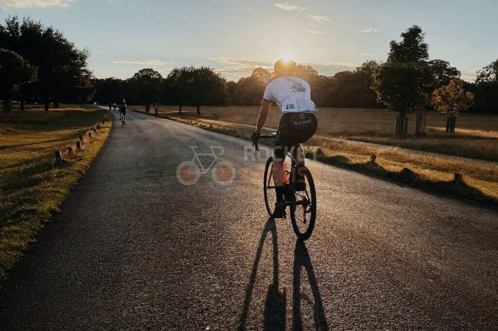A cyclist riding down a country road at sunset.